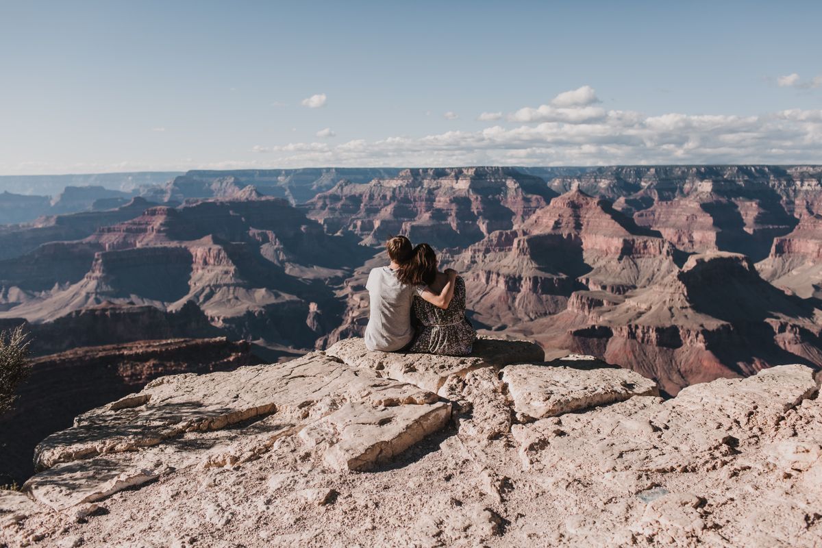 Couple sitting at the rim of the Grand Canyon taking in the view