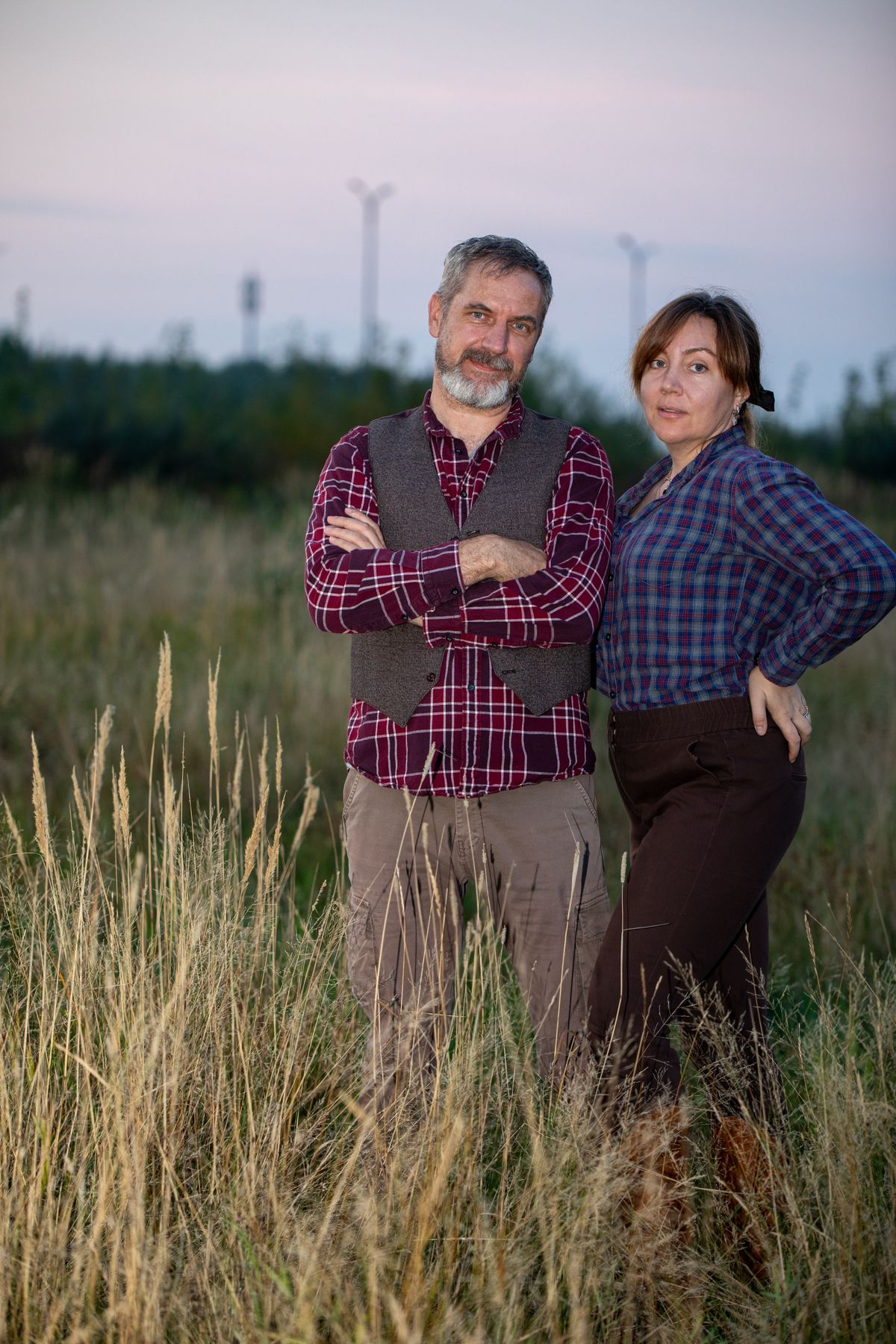 Couple standing together in a field at dusk